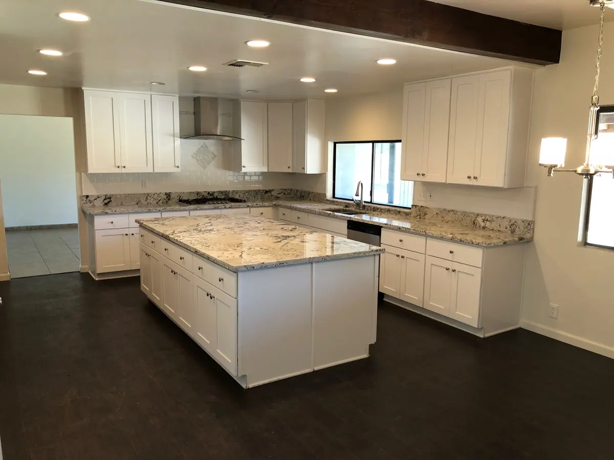 Finished white kitchen with a granite island and full appliance run