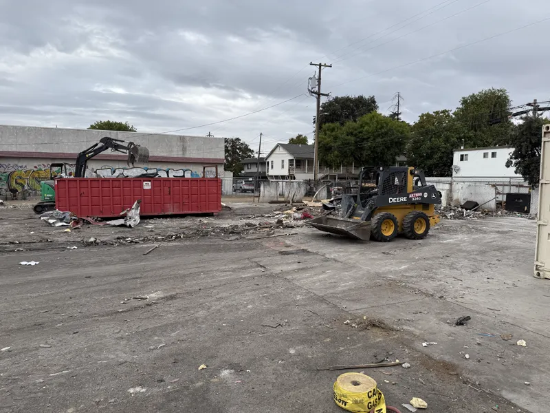 Commercial lot with the structure gone, the slab swept and the last bin and skid steer still on site
