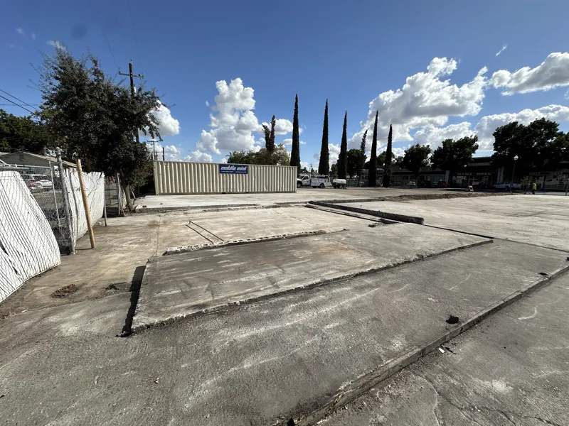 Cleared commercial slab with a storage container set along the boundary and the footprint of the old building visible