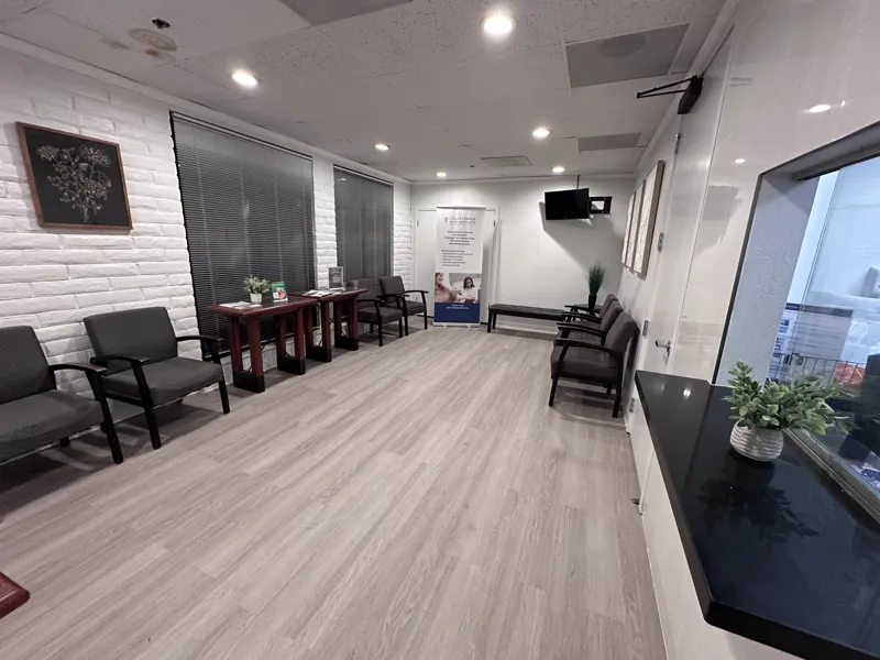 Finished dermatology clinic waiting room with painted brick, wood-look vinyl plank flooring, recessed lighting and patient seating