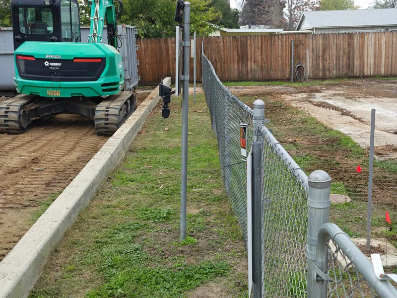 New concrete curb and reinstated chain-link boundary alongside the cleared pad