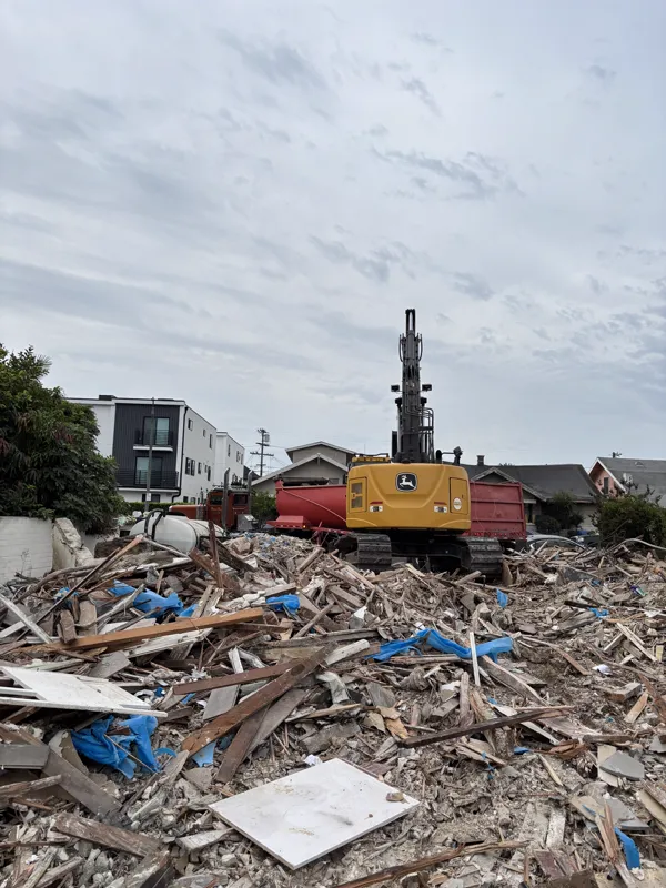 Mobile home broken down into a sorted debris pile of timber and panel, staged beside the bin