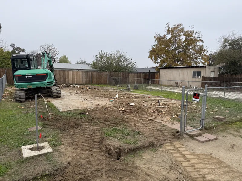 Back-yard pad cleared down to the original concrete after a mobile home removal, utilities capped and flagged