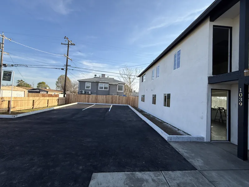Finished parking lot, new timber fence and concrete walkway beside the completed apartment building