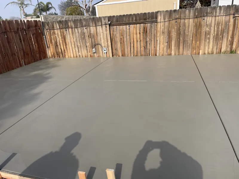 Finished residential concrete slab troweled smooth and jointed, running wall to wall behind the fence