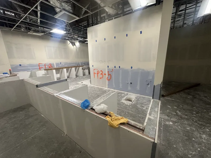 Boarded counter bulkheads and service openings formed in a commercial fit-out before finishes