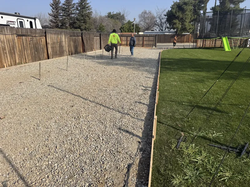 Crew spreading and raking base rock inside the timber forms for a new residential RV pad